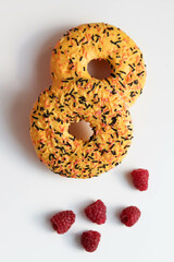 sweet dessert. round donuts with yellow icing isolated on white background and raspberries