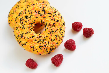 sweet dessert. round donuts with yellow icing isolated on white background and raspberries