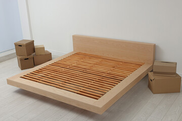 New wooden bed frame and moving boxes indoors