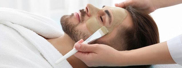Obraz na płótnie Canvas Cosmetologist applying mask on client's face in spa salon. Banner design