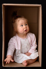 Fototapeta premium Happy little girl sitting in a cardboard box and having fun