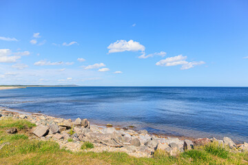 Fototapeta na wymiar A scenic view of Scottish seaside with majestic blue sea along rocky beach under a beautiful blue sky and some white clouds