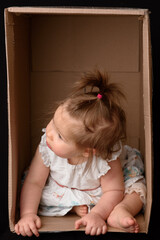 Fototapeta premium Happy little girl sitting in a cardboard box and having fun