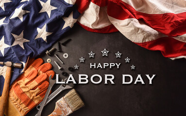 Happy Labor day concept. American flag with different construction tools and the text on dark stone background.