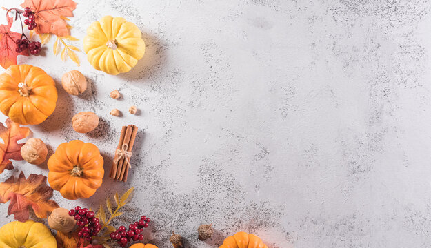 Autumn and thanksgiving decoration background concept with fall leaves, pumpkin and seasonal autumnal decor on stone background, top view, copy space.