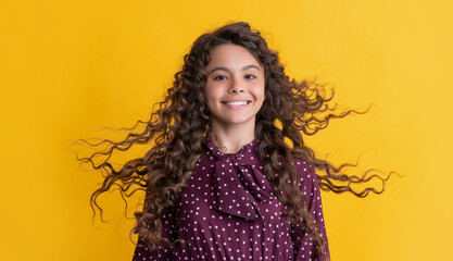 happy girl with long brunette curly hair on yellow background - obrazy, fototapety, plakaty