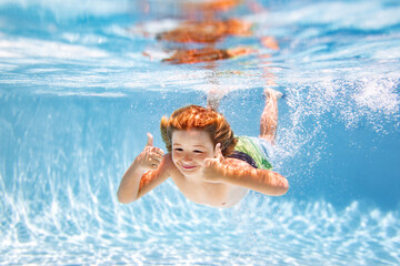 Child boy swimming underwater in swimming pool. Funny kids boy play and swim in the sea water.