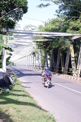 person riding a bike or iron bridge or jembatan konstruksi besi di kali Luk Ulo, Kebumen, Jawa Tengah, Indonesia - obrazy, fototapety, plakaty