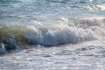 Splashes of water and foam against the sea on a sunny summer day