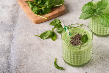 Spinach smoothie healthy green. Vegan smoothie or milkshake from spinach, banana and chia seeds on gray concrete table background. Clean eating, alkaline diet. Top view. Mock up.