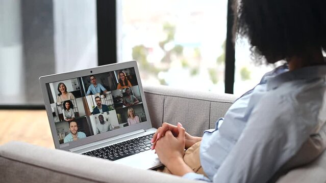 Side view of multiracial woman sitting at the laptop, chatting with friends or colleagues via video meeting, discussing the new project, teaching online,making video call to group of diverse people