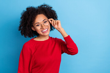Fototapeta na wymiar Photo of pretty dreamy lady dressed red pullover arms eyewear smiling empty space isolated blue color background