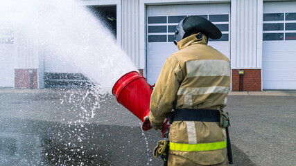 A firefighter in a protective suit and helmet.A firefighter holds a fire barrel in his hands to...