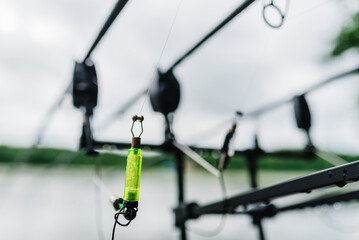 Swing fishing. Fishing rods for carp fishing with signaling devices on holder. Rod pod. Fishing for pike, perch, carp on background of lake.  Angler is fishing with carp fishing technique.