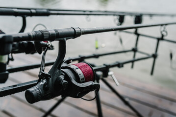 Feeder fishing with reel close up. Fishing rods for carp fishing with signaling devices on the holder. Rod pod. Fishing for pike, perch, carp on lake. Angler is fishing with carp fishing technique.