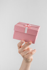 Child hand holding gift box with pink bow. white and gray background with copy space