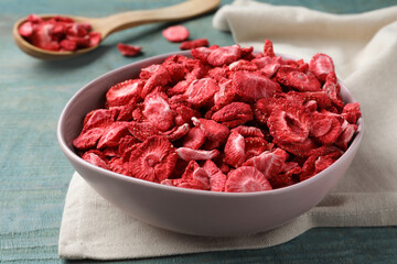 Bowl with dried strawberries on light blue wooden table, closeup