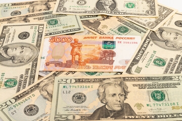 Russian national currency on top of US dollar banknote, top view of mixed rouble banknotes. Russian and American paper money. Rubles and US dollars exchange rate.