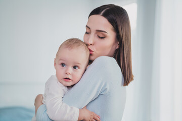 Portrait of charming peaceful lady hold kiss head adorable toddler support trust house indoors