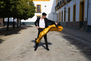 Portrait of young and handsome gipsy man, dressed in black and red shoes dancing with a black and...