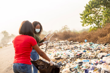 two young beautiful teenagers wearing face mask whist packing dirt for recycling