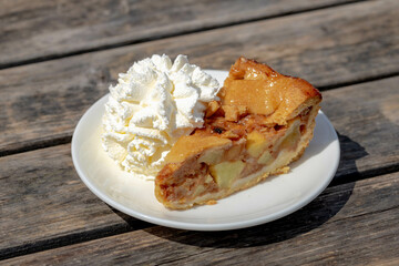 A piece of apple pie on white plate served with whipping cream on the side, Homemade apple pie on...