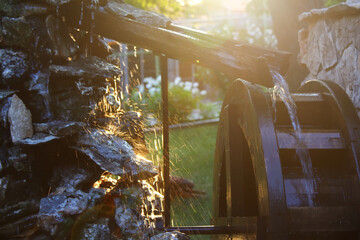 Splashes from a small water mill in the beams of the evening sunlight. Bulgaria.