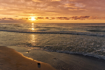Sunset on Baltic Sea white bright golden orange color and rough sea