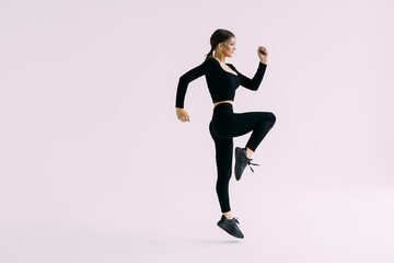 Portrait of a smiling fitness woman jumping isolated over white background