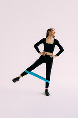 Sportswoman doing workout with resistance band, stretching elastic rope, exercising for fit and strong body in gym on white background