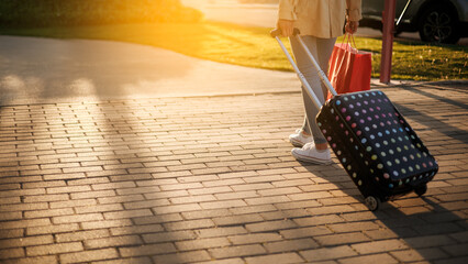 Unrecognizable woman crossing street with suitcase, travel concept, copy space