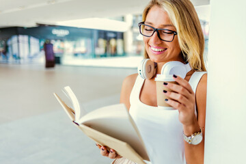 Cropped shot of an attractive woman reading a book and drinking a cup of coffee. Shot of a...