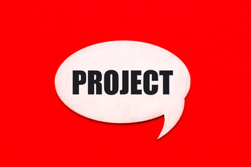 On a bright red background, a light wooden curly card with the text PROJECT