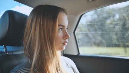 A young girl rides in a car in the back seat.