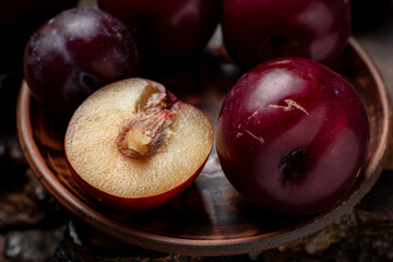 Fresh sliced red plums on a dark wooden background.