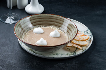 Plate of Cream Cappuccino Soup with Porcini Mushrooms and Truffle on Black Stone
