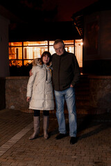 Fototapeta na wymiar elderly couple standing in courtyard of house on autumn evening....