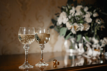champagne glasses on the table. Wedding rings on the table. Wedding rings on the table near champagne and a bouquet
