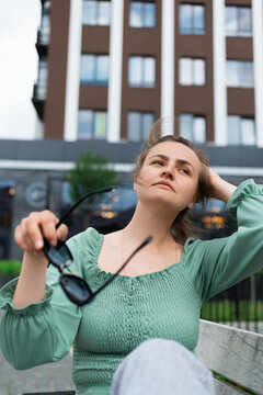 A Woman Is Putting On Sunglasses On A Hot Summer Day