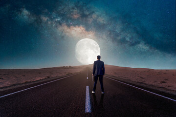 silhouette of a business person walking on the road towards the lunar horizon at night