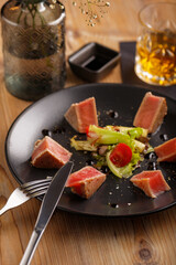 a culinary dish salmon steak on a black plate on a wooden table. restaurant serving