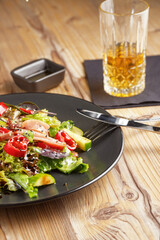 cooking dish, appetizer. Salad. Restaurant serving. black dishes, wooden table.