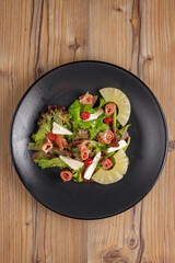 traditional dishes of European cuisine, delicacy, banquet snack. culinary dishes on a black plate on a wood background. restaurant service. top view