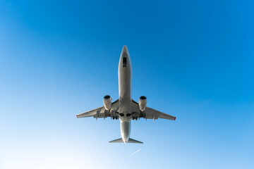 Close-up view from below of a departing plane with landing gear on a blue sky background on a sunny...