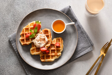 Trendy breakfast with croffles and morning coffee, strawberries on gray background. Croissant as waffle. Top view.