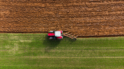 Fototapeta na wymiar Tracteur labourant un pré d'herbe en vue aérienne. Préparation de la terre avant la culture.