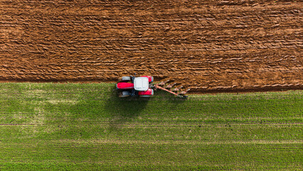 Tracteur labourant un pré d'herbe en vue aérienne. Préparation de la terre avant la culture.