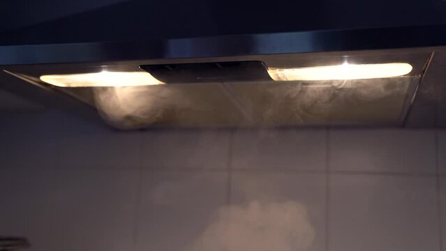 Stove hood absorbing smoke in slow motion while cooking