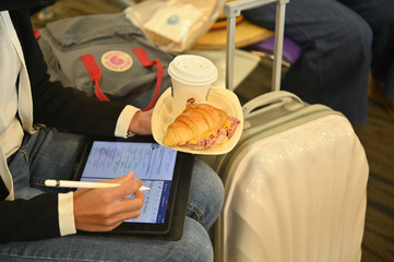 Student's fast paced lifestyle, travel, eat, study in limited time..woman holding a hamburger and...