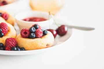 Homemade cottage cheese pancakes with fresh berries on white table. Copy space